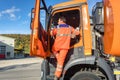 Garbage removal worker getting into the disposal vehicle