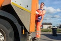 Garbage removal worker riding on the back of the disposal vehicle