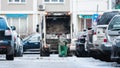 Garbage truck, dustcart with bin lift, household waste removal in residential area in winter