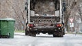 Garbage truck, dustcart with bin lift, household waste removal in residential area in winter, refuse container, snow