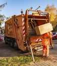 A garbage truck used to collect and shred bulky items from households. A worker is carrying a piece of furniture to the truck