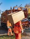 A garbage truck used to collect and shred bulky items from households. A worker is carrying a piece of furniture to the truck Royalty Free Stock Photo