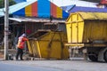 Garbage worker is moving yellow dumpster on garbage truck into community dump area