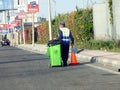 a garbageman worker in protective clothing walking with a dustbin collecting garbage for trash removal