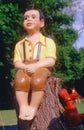 Garden art sculpture of boy sitting on wooden stump Royalty Free Stock Photo