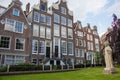 Garden of Begijnhof with ancient buildings and Christ statue. Famous medieval yard with sculpture of Jesus Christ in Amsterdam. Royalty Free Stock Photo