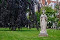 Garden of Begijnhof with ancient Jesus Christ statue. Famous medieval yard with sculpture of Jesus Christ in Amsterdam. Royalty Free Stock Photo