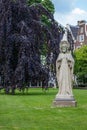 Garden of Begijnhof with ancient Jesus Christ statue. Famous medieval yard with sculpture of Jesus Christ in Amsterdam. Royalty Free Stock Photo
