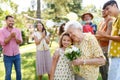 Beautiful senior birthday woman receiving flowers from granddaughter. Royalty Free Stock Photo