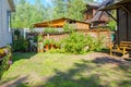 Garden buildings in the country. Shed with a canopy, bench and a street lamp and stack of the firewood over red currant bushes Royalty Free Stock Photo