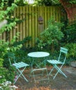 Garden chairs and table in a relaxing, serene, peaceful, lush and private home backyard in summer. Green metal patio