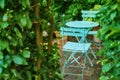 Garden chairs and table in a serene, peaceful, lush, private home backyard. Metal patio furniture set and seating in Royalty Free Stock Photo