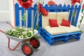 Garden composition of wheelbarrow, flowers, sofa and pillows