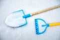 A child`s toy spade and rake left outside in the snow