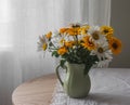 Garden daisies in a ceramic jug on a round wooden table in the living room Royalty Free Stock Photo
