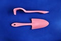 Garden equipment pink shoulder blade and rake on a blue background close-up