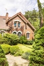 A garden with evergreens, trees, shrubs and grass in the backyard of a red brick luxurious English style house. Royalty Free Stock Photo