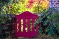 Garden fence in autumn - decrative magenta fence in rock wall surrounded with foliage and fall trees in background Royalty Free Stock Photo