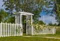 Beautiful white gate in the flowers on a sunny summer day. Garden gate with White Picket Fence Royalty Free Stock Photo