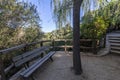 A garden with a gazebo with a wooden railing and a bench made of the same material