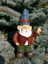 Garden gnome in fir forest makes peace sign