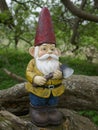 Garden gnome with an ax in his hand stands on the withered branch of an old tree trunk Royalty Free Stock Photo