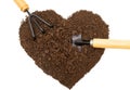 Garden hand tools in a heart shaped heap of soil
