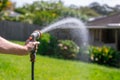 Garden hose with nozzle. Man's hand holding spray gun and watering plants, spraying water on grass in backyard Royalty Free Stock Photo