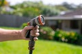 Garden hose with nozzle. Man\'s hand holding spray gun and watering plants, spraying water on grass in backyard Royalty Free Stock Photo
