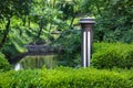 Garden iron lantern with white diffuser of street lighting in deciduous boxwood bush.