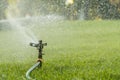 Garden irrigation system watering lawn. watering the lawn in the hot summer. Lawn sprinkler spaying water over green grass. Irriga Royalty Free Stock Photo