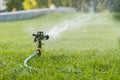 Garden irrigation system watering lawn. watering the lawn in the hot summer. Lawn sprinkler spaying water over green grass. Irriga Royalty Free Stock Photo