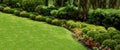 Garden landscape with flower bed of green bushes and green meadow lawn. Royalty Free Stock Photo