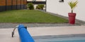 Garden lawn and swimming pool detail with bubble wrap reel