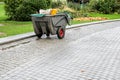 Garden maintenance cart with tools on wet cobblestone path in public park Royalty Free Stock Photo