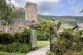 Garden of Ninfa in Italy with the gate, medieval tower and hills in the background.