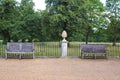 Garden ornament on a pedestal and wooden benches, seat. Royalty Free Stock Photo