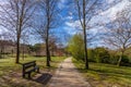 Garden or park bench near an empty dirt path, track, trail or pathway through the trees and green grass lawn