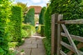 Garden path past open gate between trees Royalty Free Stock Photo