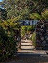 Garden path with rock feature wall, arch doorway along stone walkway surrounded by trees