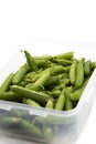 Garden peas in pods freshly picked in a plastic container,  isolated on a white background. Royalty Free Stock Photo