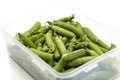 Garden peas in pods freshly picked in a plastic container,  isolated on a white background. Royalty Free Stock Photo