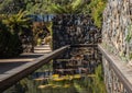 Garden pond, rock feature wall, path to arch doorway surrounded by trees