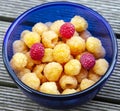 Garden raspberries of yellow and red varieties in a blue glass container Royalty Free Stock Photo