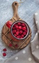 In the foreground is a red mug with garden raspberries, in the background a cheesecake with berry filling, light background, defoc