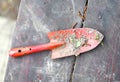 Garden red spade shovel close up photo with soil on the wooden bench