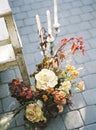 Garden roses bouquet and chandelier with candles next to a wooden seat on tiled floor