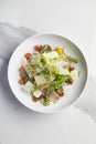 Garden salad with parma ham in white plate on white marble background Royalty Free Stock Photo