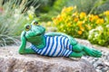 A garden sculpture of a frog lying on the floor reading a book