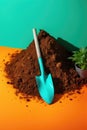 A garden shovel with soil and a small pot with a plant on an orange green background, Generative AI